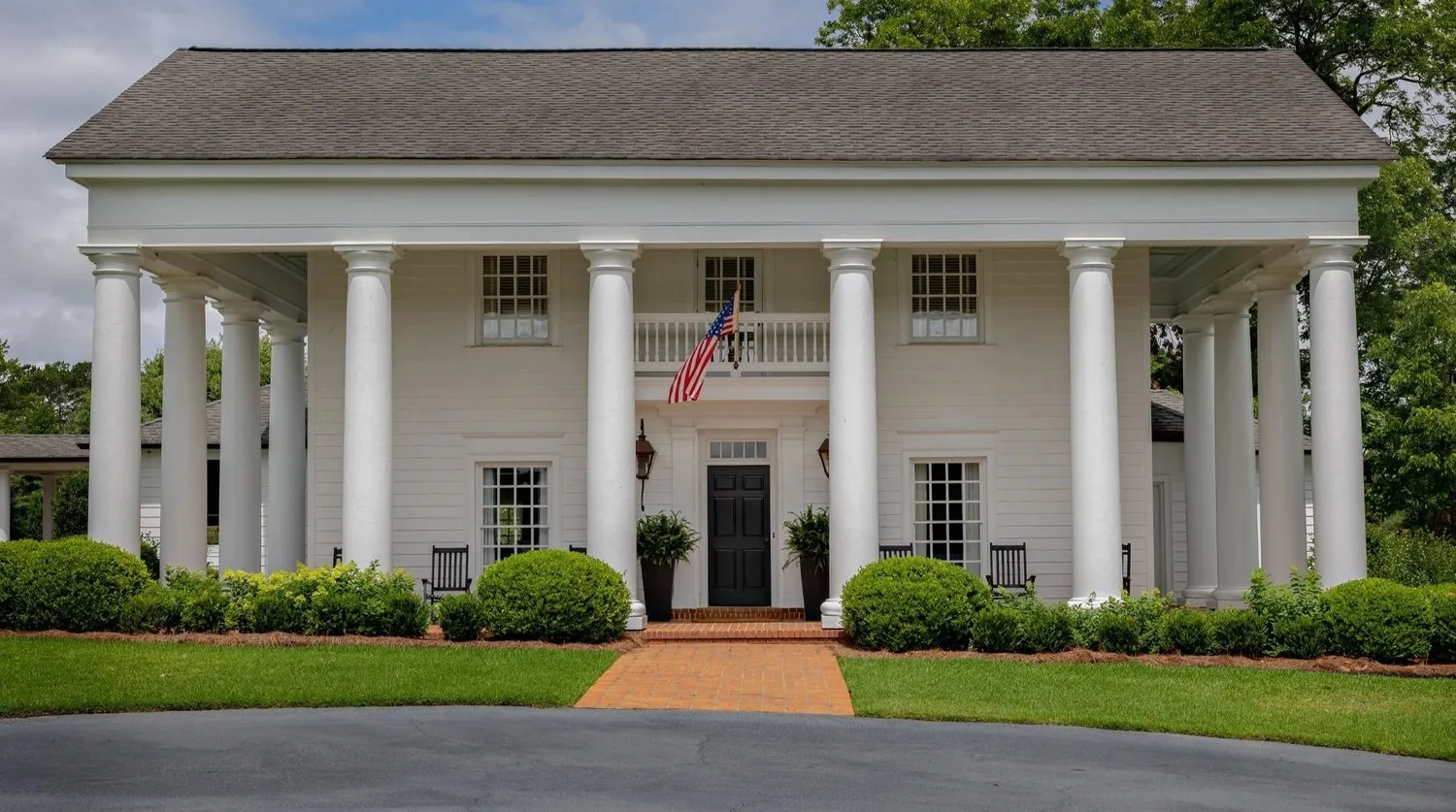 Grove Hill Farm: a white farmhouse behind a clipped lawn and mature trees.